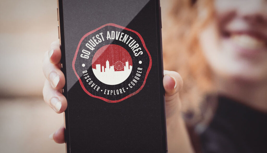 A person holding a smartphone displaying a beautifully crafted logo design that reads "Go Quest Adventures - Discover. Explore. Conquer." with an intricate city skyline in the background.