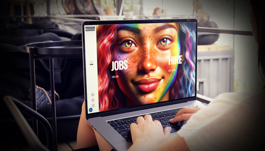 A person using a laptop with a colorful portrait of a woman on the screen, navigating through options for "Jobs" and "Hire" on a website design platform.